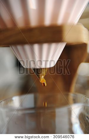 Close Up Coffee Dripping. Alternative Brewing In Pink Ceramic Origami Dripper On Wooden Stand.