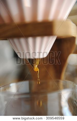 Close Up Coffee Dripping. Alternative Brewing In Pink Ceramic Origami Dripper On Wooden Stand.