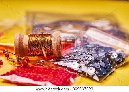 Embroidery Products And Tools. Coil Of Metal Thread, Japanese Beads And Sequins With Pin And Needles