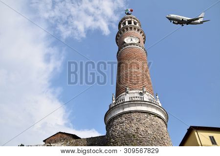 A Plane Flies Over The Tower Of The People In Palazzolo On The Oglio River - Italy