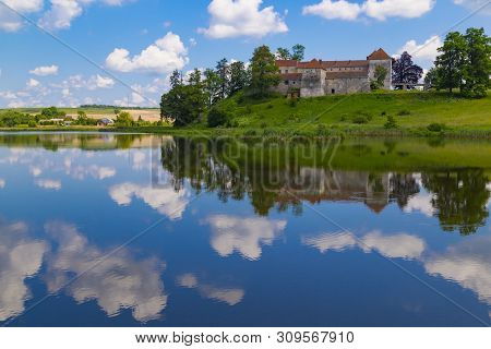 Castle On The Lake. Beautiful Scene With Ancient Svirzh ( Svirz ) Castle On The Hill Against The Blu