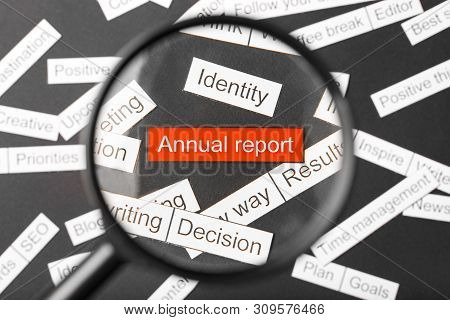 Magnifier Glass Over The Red Inscription Annual Report Cut Out Of Paper. Surrounded By Other Inscrip