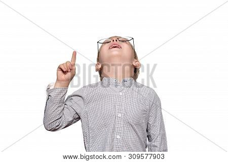Portrait Of A Cute Blond Boy With Big Glasses. He Looks Up And Points A Finger. Isolate