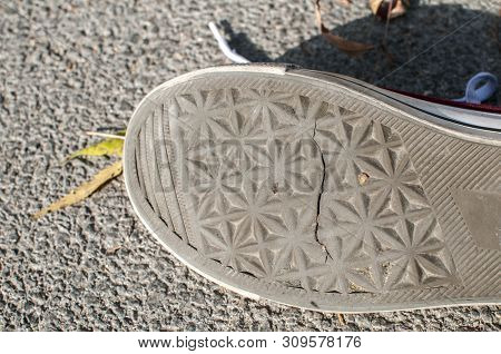 A Sneaker Cracked Rubber Outsole Closeup On Asphalt Background