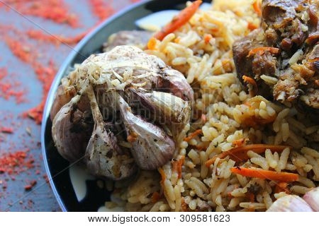 Pilaf On A Platter Of Meat And Spices.pilaf In A Plate On A Wooden Background, Top View. The Concept