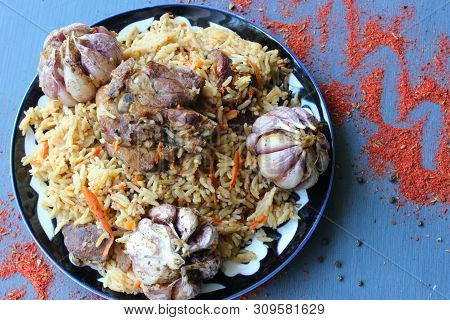 Pilaf On A Platter Of Meat And Spices.pilaf In A Plate On A Wooden Background, Top View.  The Concep
