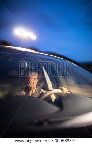 Young female driver at the wheel of her car, super tired, falling asleep while driving in a potentially dangerous situation - Road safety concept