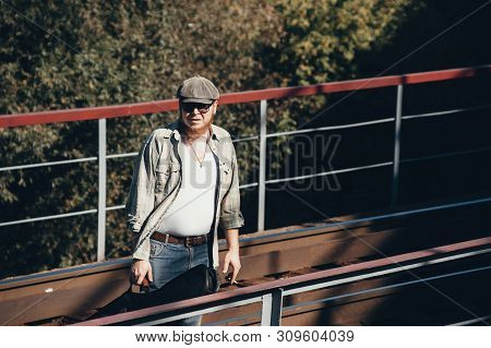 Bluesman With Guitar Case Smokes Cigarette On Railroad. Blues Musician With Cigarette On Railway. Co