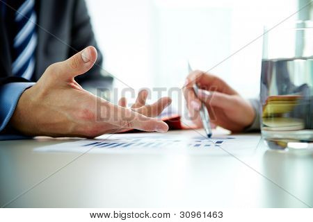 Bilden av manlig hand pekar på affärsdokumentet under diskussionen vid mötet