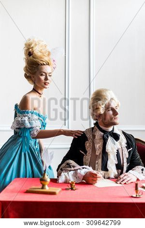 Selective Focus Of Victorian Woman In Wig Standing Near Pompous Man Holding Feather