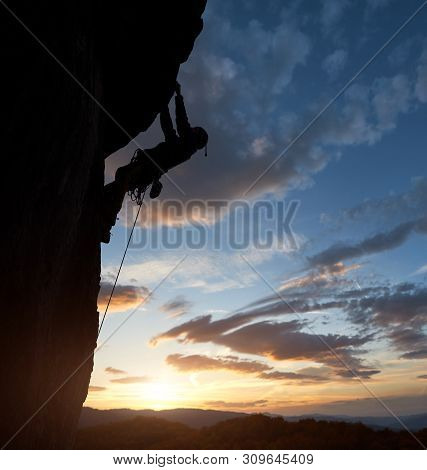 Athletic Man Silhouette Climbing In Safety Harness On Overhanging Cliff Rock High Up Over Mountains 