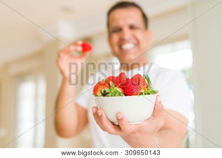Middle age man eating straweberry at home