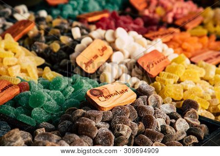 Colorful Sugar Sweets Gums And Jelly Beans On Market. Text On The Wooden Board: 