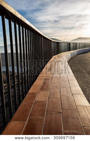 Metallic And Wooden Railing On A Coast Cliff Illuminated By The Sunset Light At Costa Brava (spain)