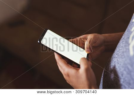 Man Hand Holding Mobile Phone In Coffee Shop. Man Using Smartphone. Empty Screen With Copy Space For