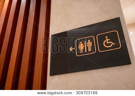 Restroom Sign Made Of Gold Metal On Black Board Hanging On White Wall