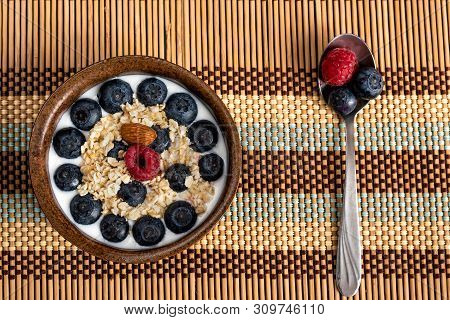 The Concept Of Health. Yoghurt Bowl With Oat Flakes, Blueberries, Raspberries And Almond On A Wooden