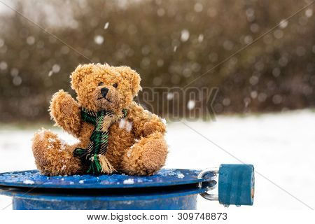 Plush Teddy Bear On Blue Lid With Blue Lock In Snowy Landscape With Blurred Background.