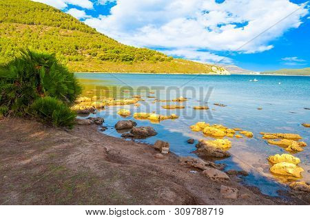 View Of Gulf, Pier And Beach Of Tramariglio In A Sunny And Cloudy Day, In The Capocaccia Coast