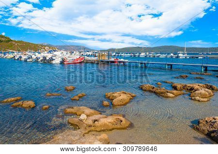 View Of Gulf, Pier And Beach Of Tramariglio In A Sunny And Cloudy Day, In The Capocaccia Coast