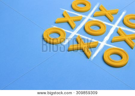 Yellow Plastic Crosses And A Toe And A Ruled Field For Playing Tic-tac-toe On A Blue Background. Con