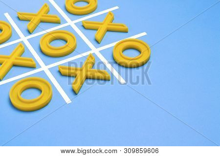 Yellow Plastic Crosses And A Toe And A Ruled Field For Playing Tic-tac-toe On A Blue Background. Con