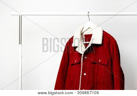 Red Corduroy Men's Jacket On White Coat Hanger On Rod Against Light Wall Flat Lay Copy Space. Male F