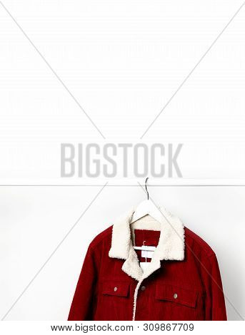 Red Corduroy Men's Jacket On White Coat Hanger On Rod Against Light Wall Flat Lay Copy Space. Male F