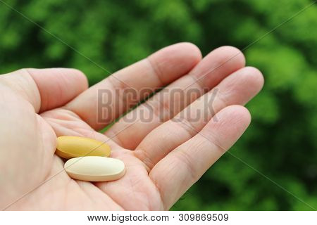 Closeup Two Different Color Supplement Tablets In Man Palm
