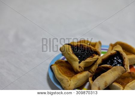 Hamantash Purim Blueberry And Apricot Jam Cookies On Colored Plate With White Sheet Background