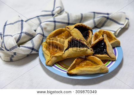 Hamantash Purim Blueberry And Apricot Jam Cookies On Colored Plate With A Plaid Blue Rag And A White