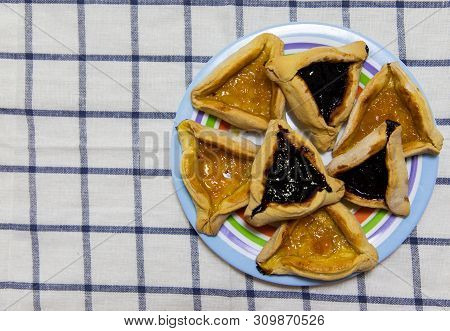 Hamantash Purim Blueberry And Apricot Jam Cookies On Colored Plate On Tablecloth With Blue Squares B