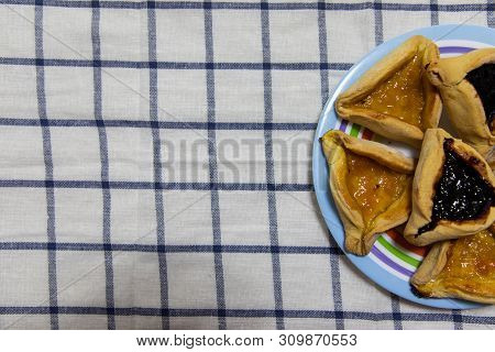 Hamantash Purim Blueberry And Apricot Jam Cookies On Colored Plate On Tablecloth With Blue Squares B