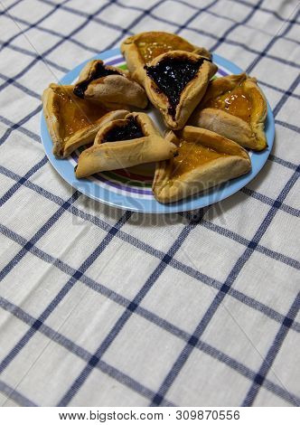 Hamantash Purim Blueberry And Apricot Jam Cookies On Colored Plate On Tablecloth With Blue Squares B