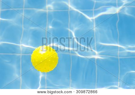 Water Vibrations In The Swimming Pool With Sun Reflection And A Yellow Ball For Playing. Blue Swimmi