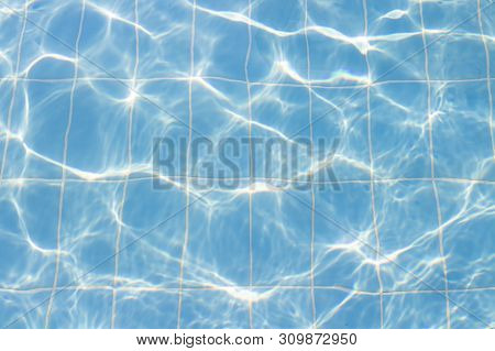 Water Vibrations In The Swimming Pool With Sun Reflection. Blue Swimming Pool Surface, Water Backgro