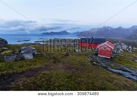 Remote Red Wooden Fredvang Hiking Cabin On Top Of A Mountain During Night On Lofoten Islands In Norw