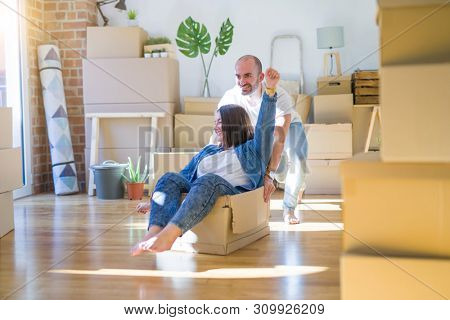 Funny and crazy couple having fun riding a cardboad box as a car, smiling happy and lauging at new home
