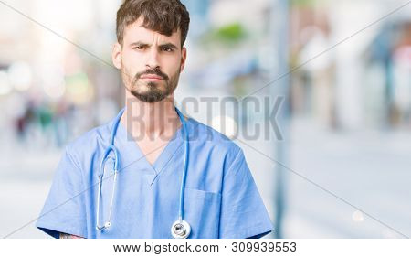Young handsome nurse man wearing surgeon uniform over isolated background skeptic and nervous, frowning upset because of problem. Negative person.