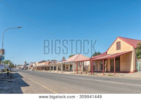 Vrede, South Africa - May 1, 2019: A Street Scene, With Businesses And Vehicles, In Vrede, In The Fr