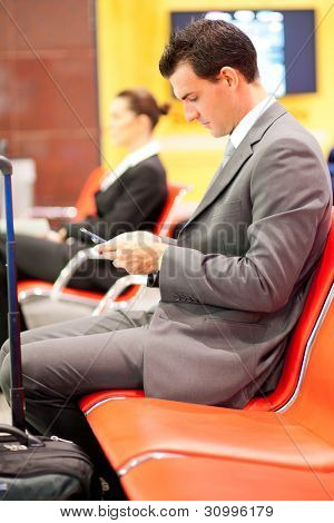 biznesmen wysyłanie i czytanie wiadomości tekstowych na lotnisku