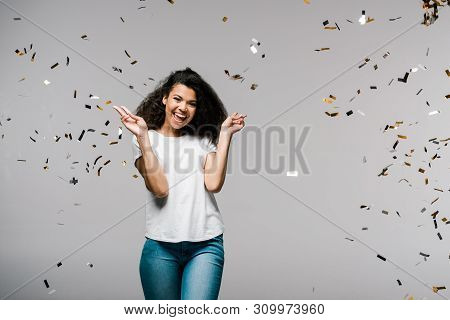 Young African American Woman Smiling Near Falling Confetti While Standing And Showing Peace Sign On 