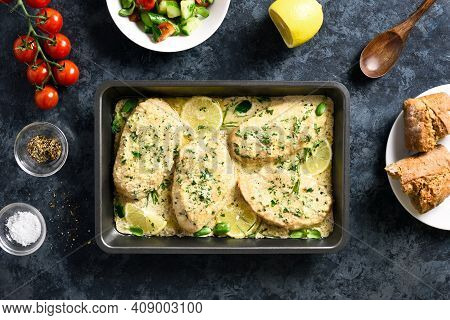 Chicken Or Turkey Breast In Creamy Garlic Sauce In Baking Dish Over Blue Stone Background. Healthy D