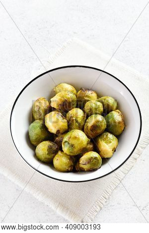 Roasted Brussles Sprouts In Bowl Over Light Stone Background With Free Text Space. Close Up View
