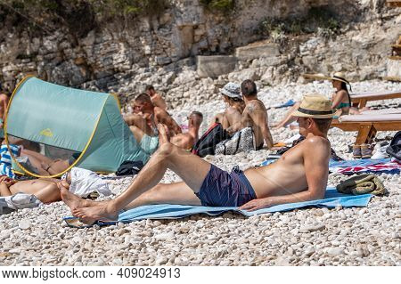 Vis, Croatia - Aug 17, 2020: Tourists Sunbathing On Sheltered Cove Stiniva Beach In Summer