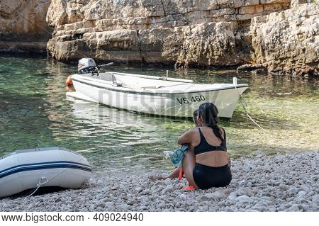 Vis, Croatia - Aug 17, 2020: Female Sit On Sheltered Cove Stiniva Beach In Summer