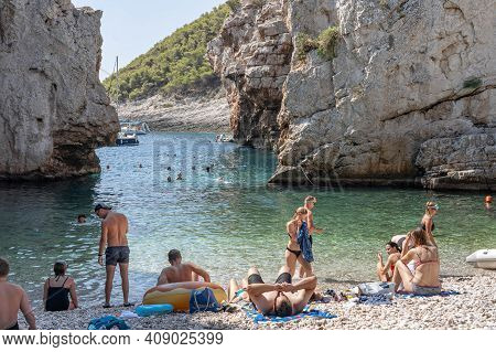 Vis, Croatia - Aug 17, 2020: Tourists Sunbathing On Sheltered Cove Stiniva Beach In Summer
