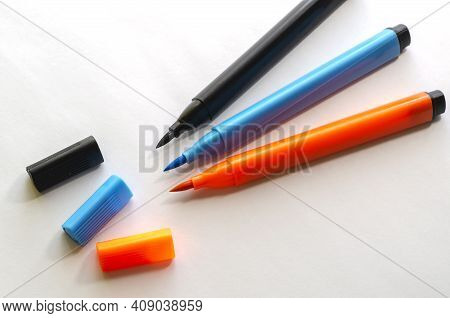 Three New Multi-colored Felt-tip Pen On A White Background. Black, Orange And Blue  Felt-tip Pens Fo
