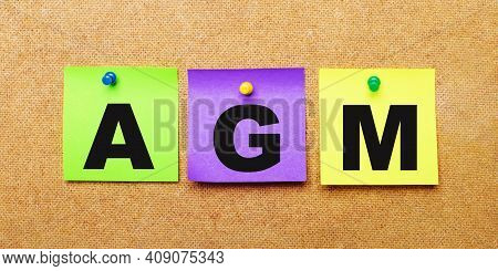 On A Beige Background, Multi-colored Stickers For Notes With The Word Agm Annual General Meeting