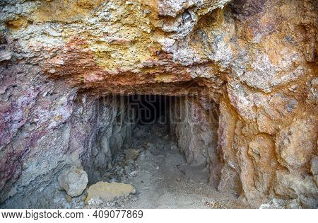 Dark Tunnel Of The Abandoned Mine With Colorful Rocks At The Entrance Rich With Copper Ore And Sulfi